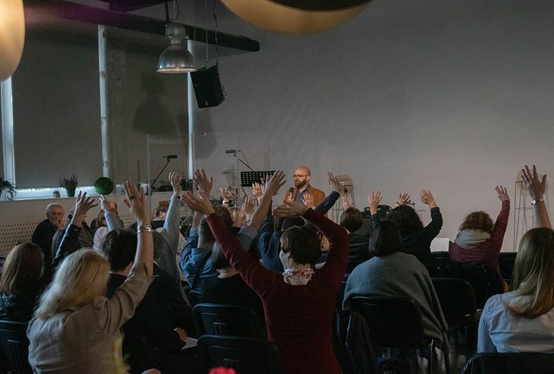 grupa uczestników spotkania podnosi ręce w górę
